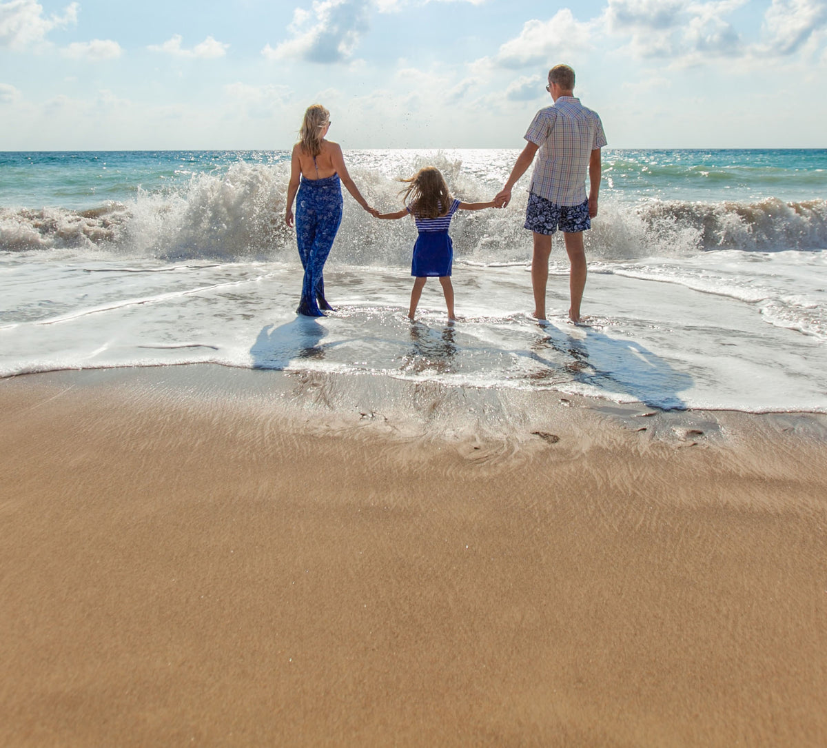 Family standing in the water on the beach